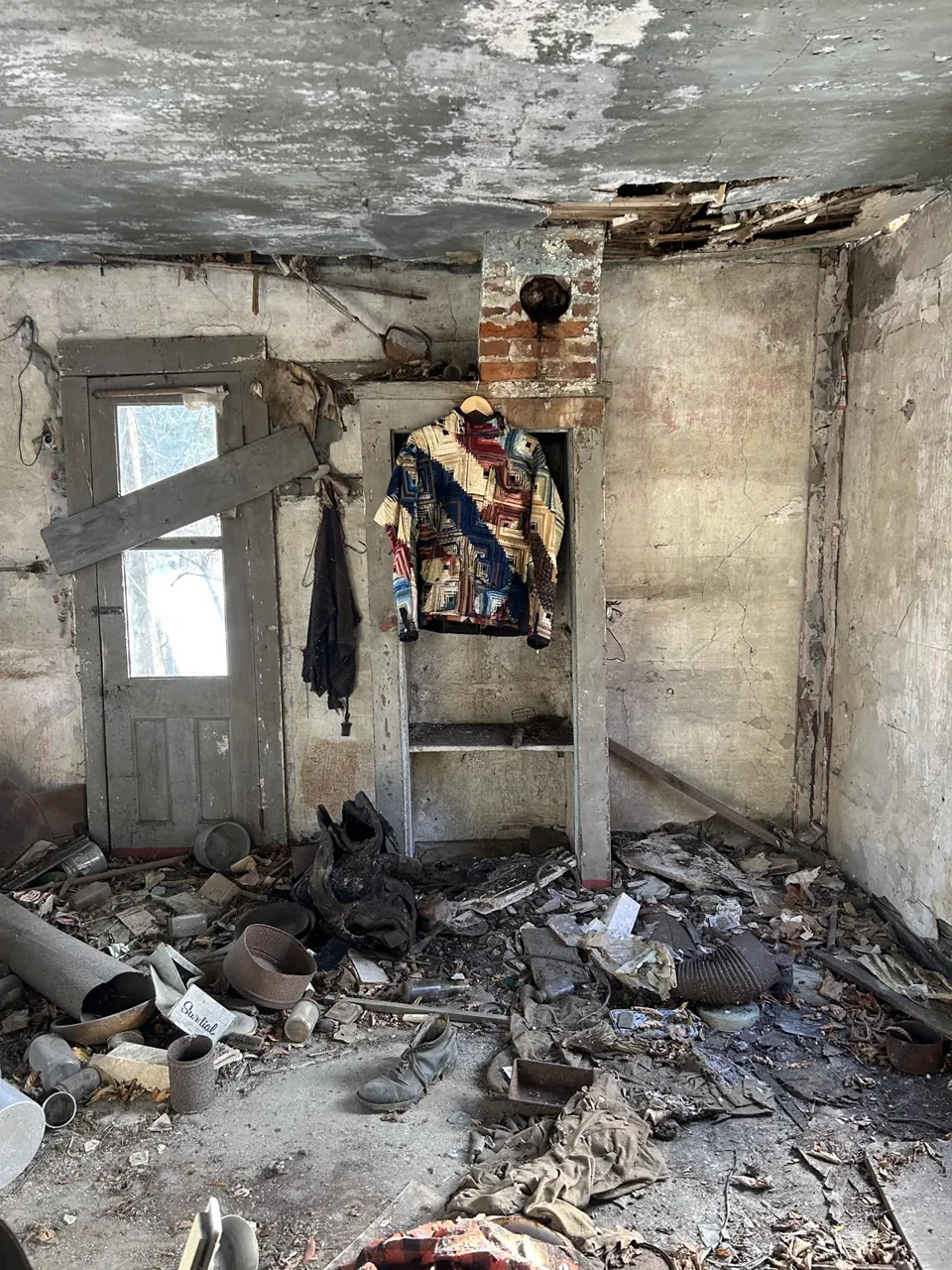 The indigo log cabin hoodie hanging inside an abandoned farmhouse