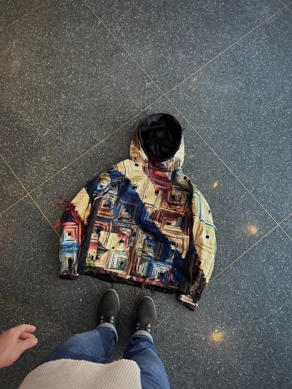 Flat lay of a log cabin quilt hoodie in indigo, madder red, and tan, set on the diagonal