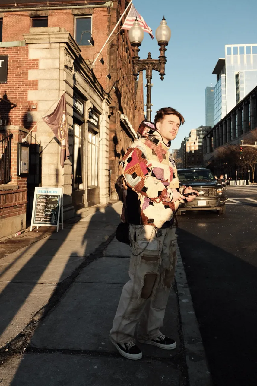 Standing on the sidewalk in the rose log cabin hoodie and patched work pants